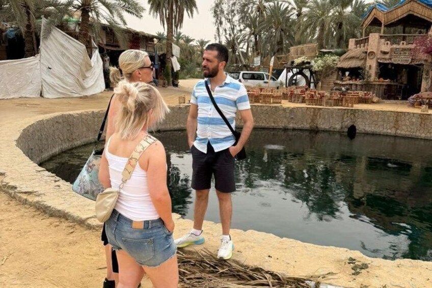A group of people standing by a pool with a traditional building in the background. 4