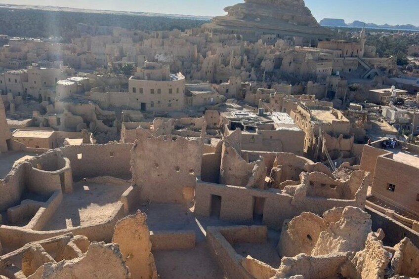A desert landscape with ancient ruins and a large, distinctive rock formation in the distance. 2