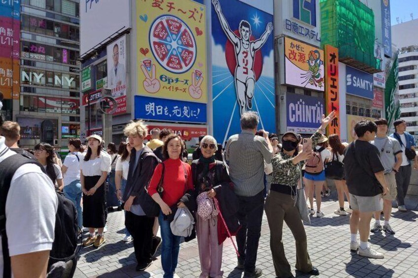A crowded urban street with people walking and taking photos. 3
