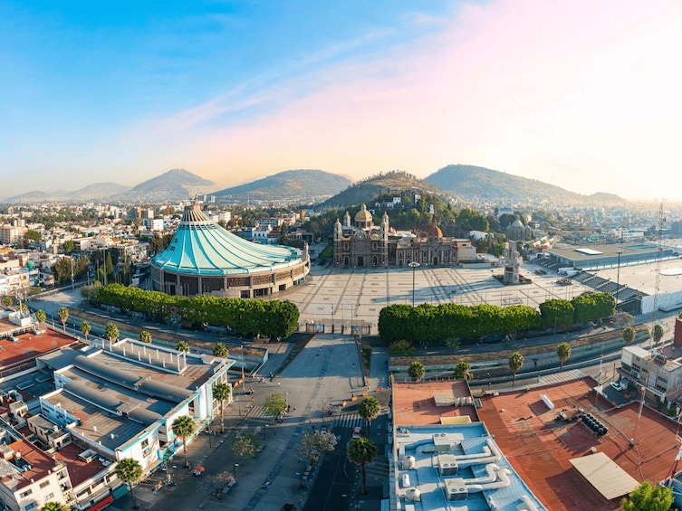 A cityscape with a prominent circular building, a large plaza, and a historic church. 2