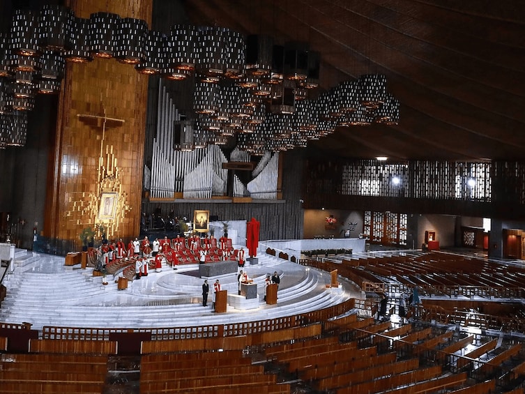 A large indoor space with a circular stage, rows of seating, and a large organ. 3