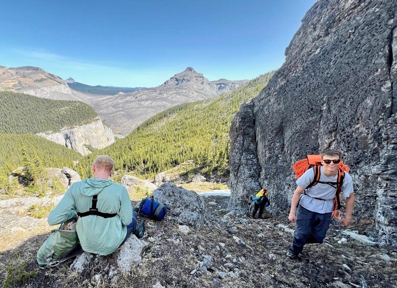 Two hikers on a rocky mountain trail with a forested valley in the background. 5