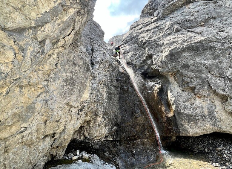 A person rappelling down a rocky cliff face. 4