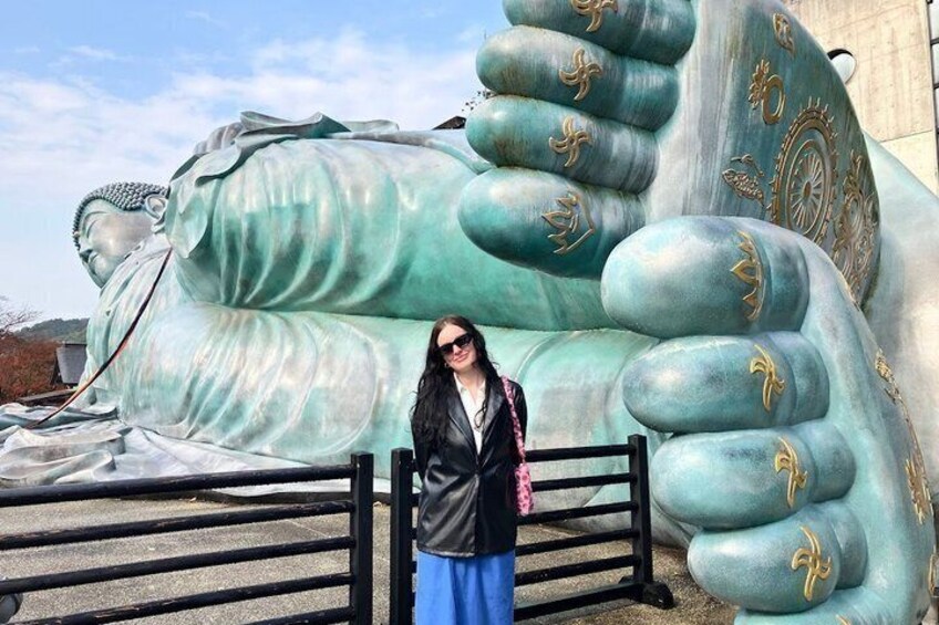 A person standing in front of a large statue with a hand motif. 5