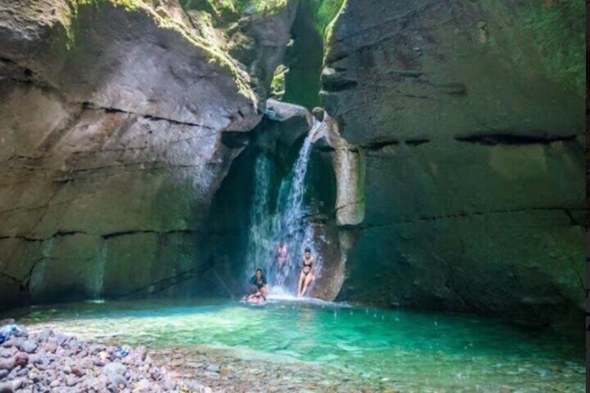 A waterfall in a rocky cave with clear water. 1