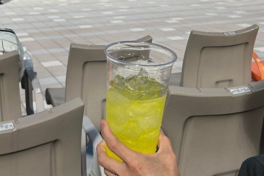A person holding a glass of yellow beverage with ice cubes. 2
