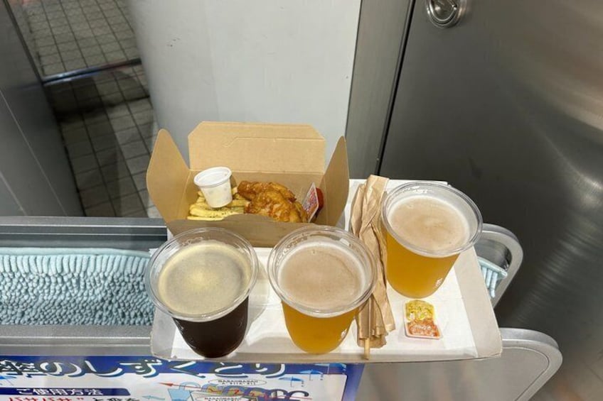 A tray with a box of fried chicken, two cups of beer, and a small container of sauce. 5