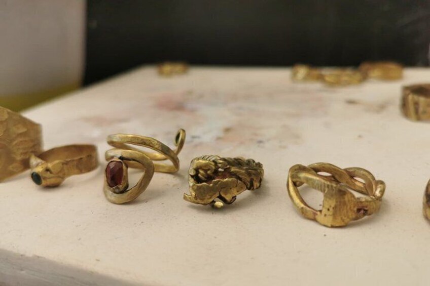 A collection of antique gold rings with gemstones on a workbench. 3