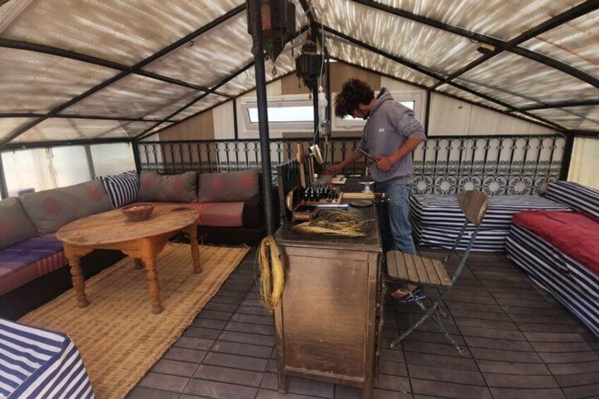 A person working at a table in a covered outdoor area with a sofa and a table. 5