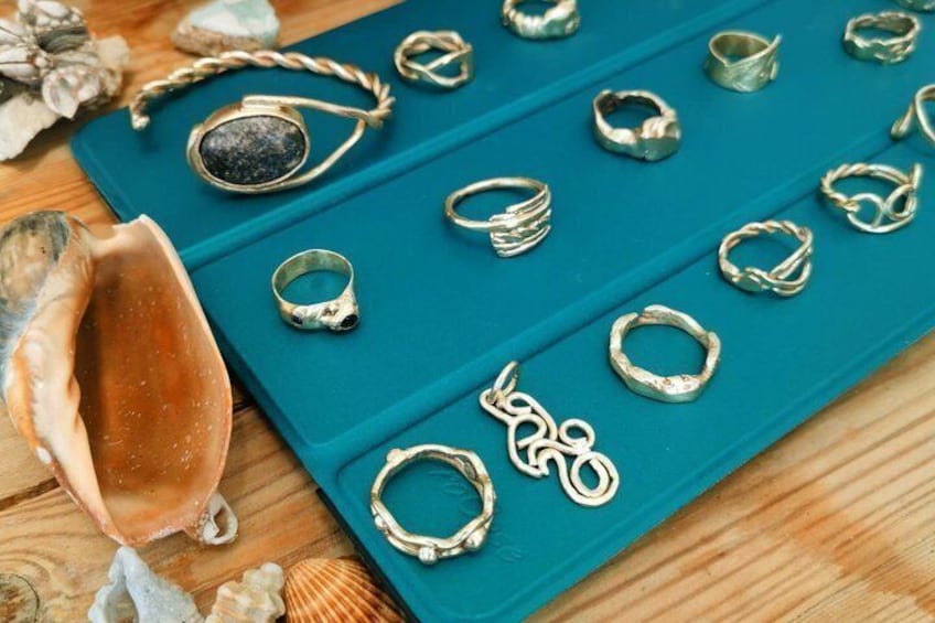 A collection of jewelry on a teal display board, including rings and a bracelet. 1