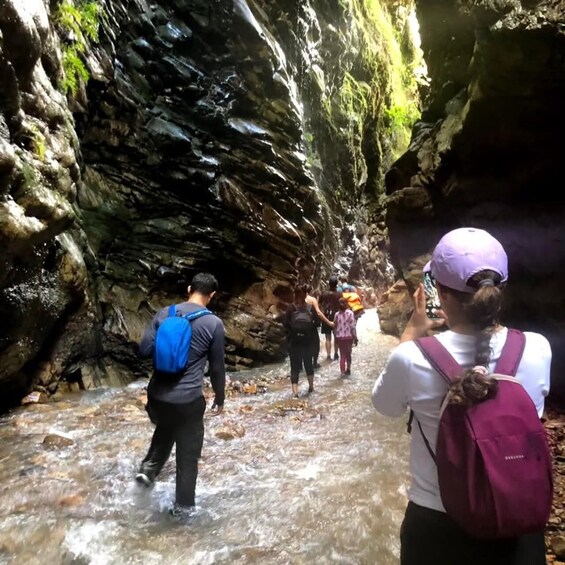 A group of people hiking through a rocky canyon with a stream. 4