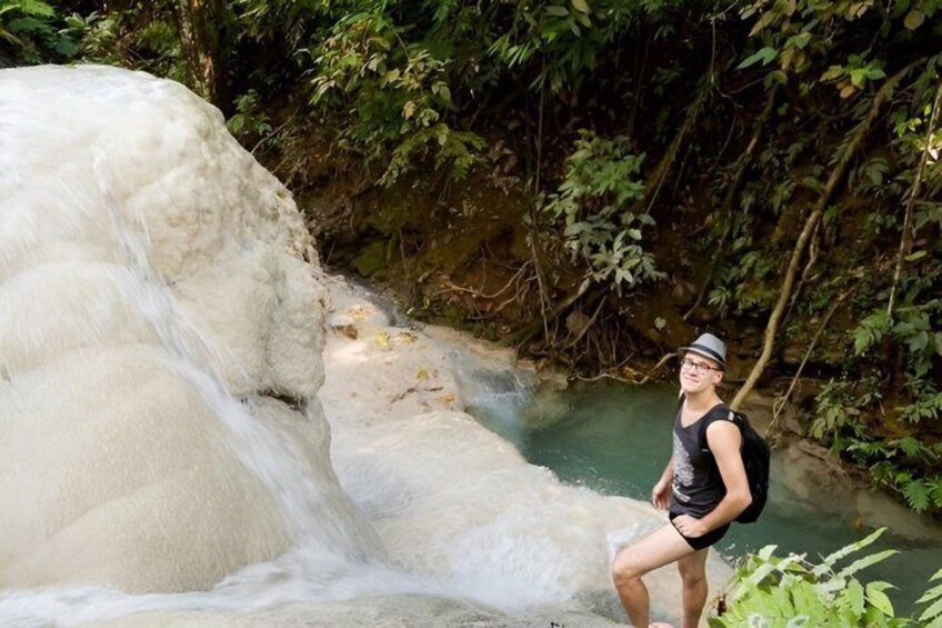 A person standing by a waterfall in a forested area. 1