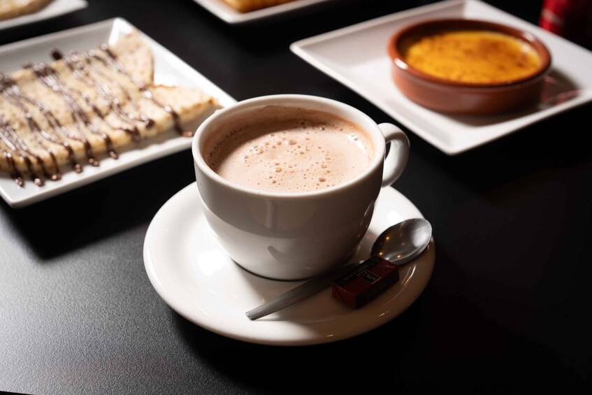 A cup of coffee with a spoon and a box of sugar cubes on a saucer. 3