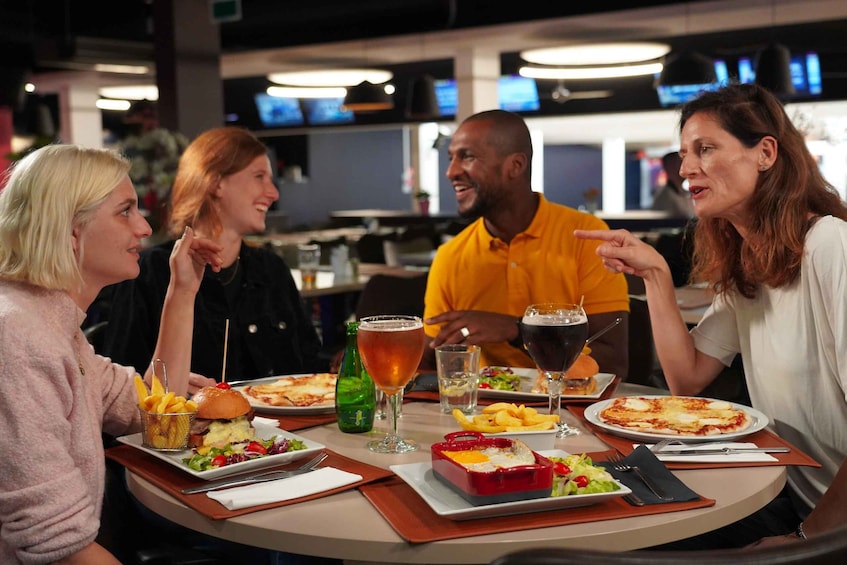 A group of people dining at a restaurant with various dishes, drinks, and a casual atmosphere. 1