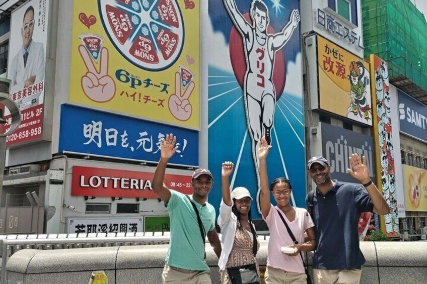 A group of people posing in front of a large advertisement featuring a cartoon character and a man lifting weights. 1
