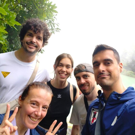 A group of people outdoors, with greenery in the background. 1