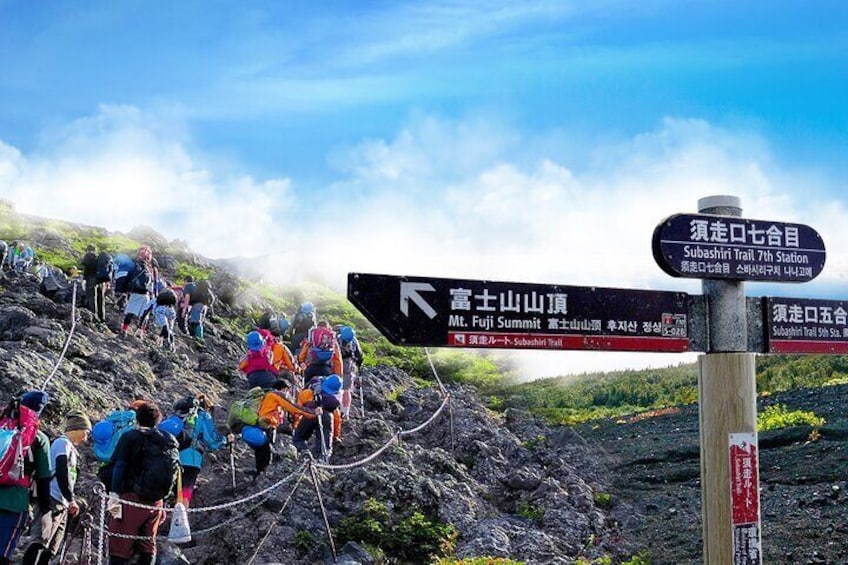 Hikers on a mountain trail with directional signs. 1