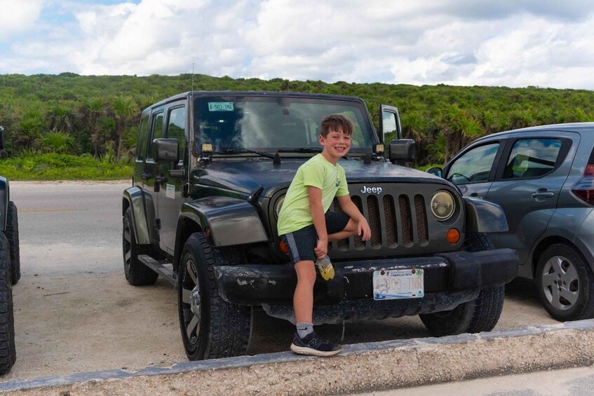 A child standing next to a black Jeep with a visible license plate. 3