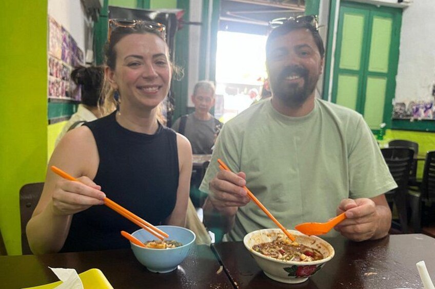 Two people sitting at a table with bowls of food and orange utensils. 5
