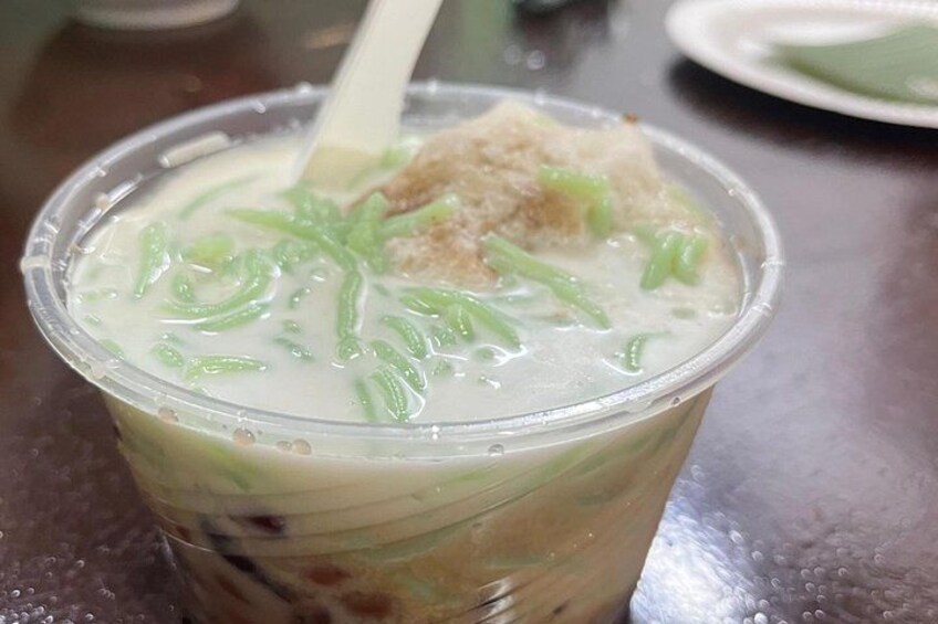 A cup of dessert with a creamy texture, topped with green strands and a piece of brown cake. 2