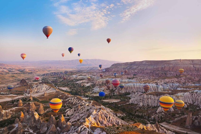 A landscape with numerous hot air balloons in a rugged terrain. 2