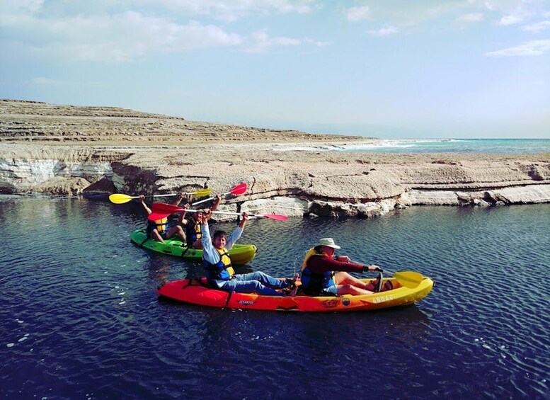 People kayaking on a calm river with rocky banks. 5