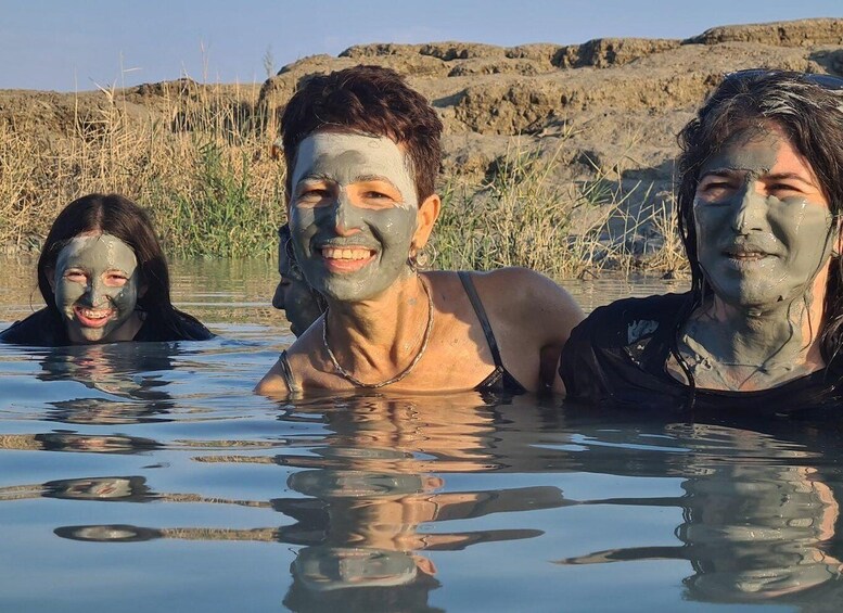 Three people in a body of water with a rocky landscape in the background. 2