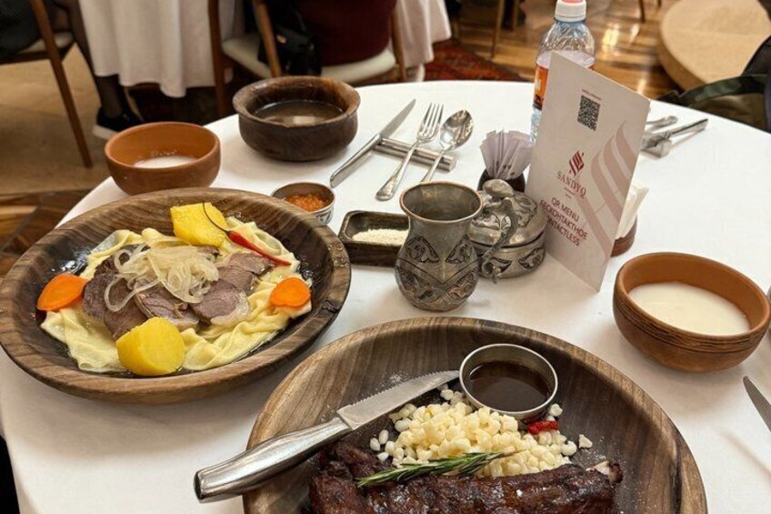 A table with a meal consisting of meat, vegetables, and a side dish, along with various bowls and utensils. 1