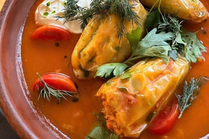 Stuffed cabbage rolls in a tomato-based sauce with dill garnish. 3