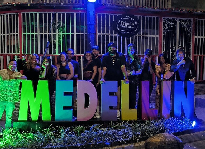 A group of people standing in front of a sign that reads 'MEDELIN.' 4