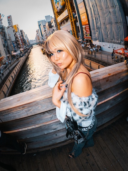 A person standing on a wooden boat in a waterway with buildings in the background. 5