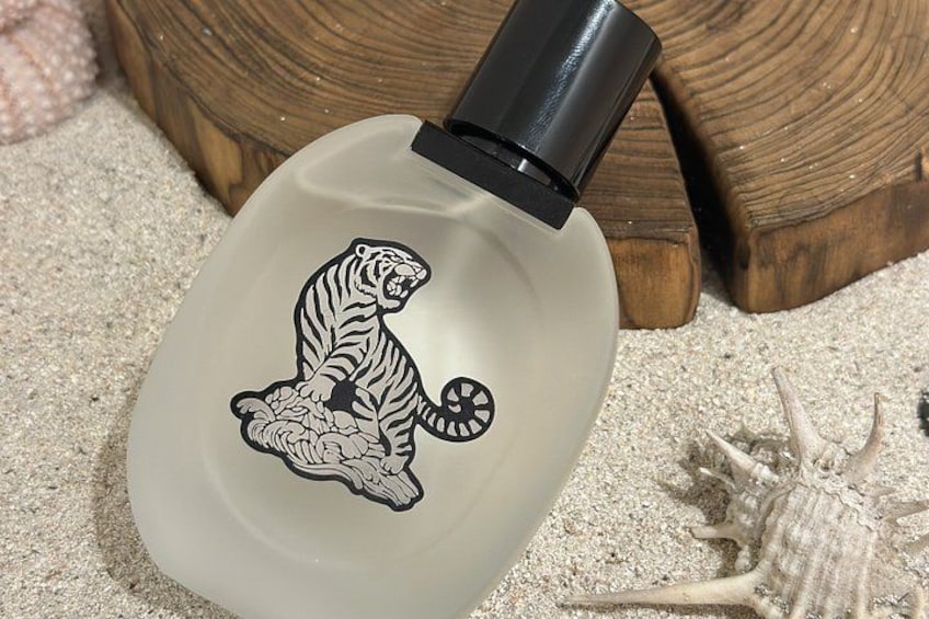 A bottle with a tiger design on a sandy surface with a starfish nearby. 3