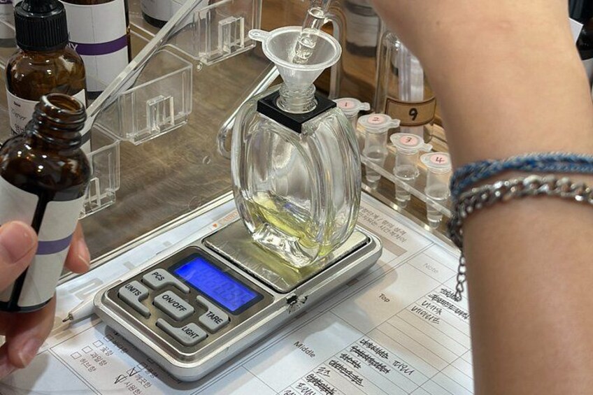 A person weighing a clear glass container on a digital scale. 5