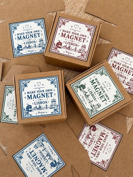 Several cardboard boxes with printed labels that say 'MAKE YOUR OWN MAGNET LISBOA.' 2