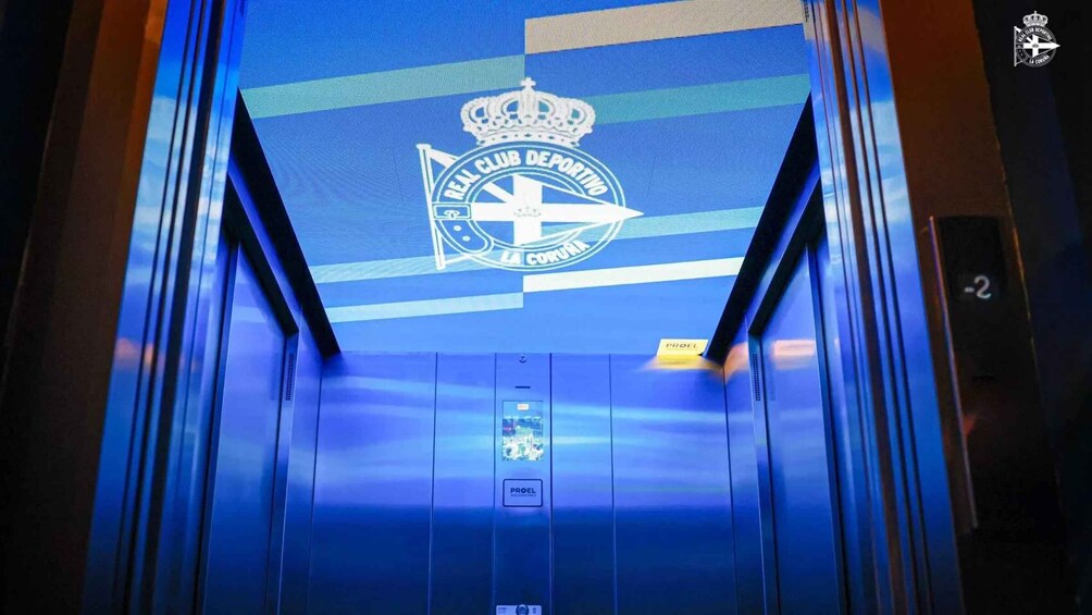 An elevator interior with a blue-lit ceiling displaying a logo and text. 5