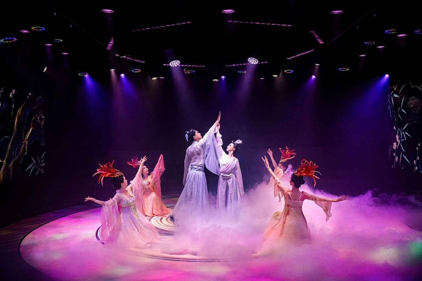 A stage performance with dancers in traditional costumes, illuminated by stage lights. 1