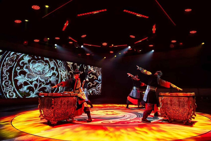 A stage with performers in traditional costumes, ornate tables, and a large illuminated screen with floral patterns. 4