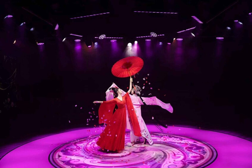 A stage with a circular patterned floor and performers in traditional attire. 2