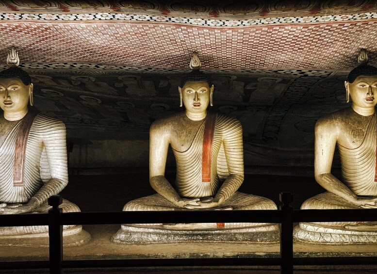 Three seated Buddha statues in a temple with intricate ceiling patterns. 4