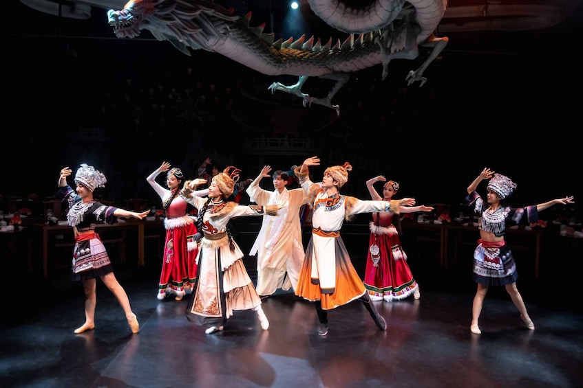 A group of dancers in traditional costumes performing on a stage with a dragon overhead. 5