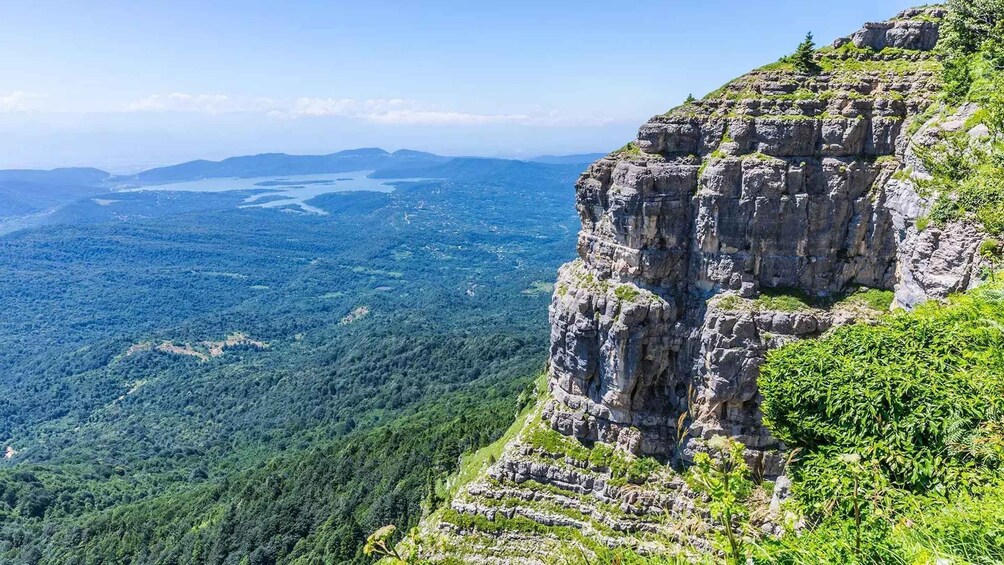 A mountainous landscape with a prominent rocky cliff and dense forest. 4