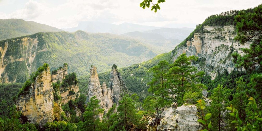 A mountainous landscape with prominent rock formations and dense forest. 3
