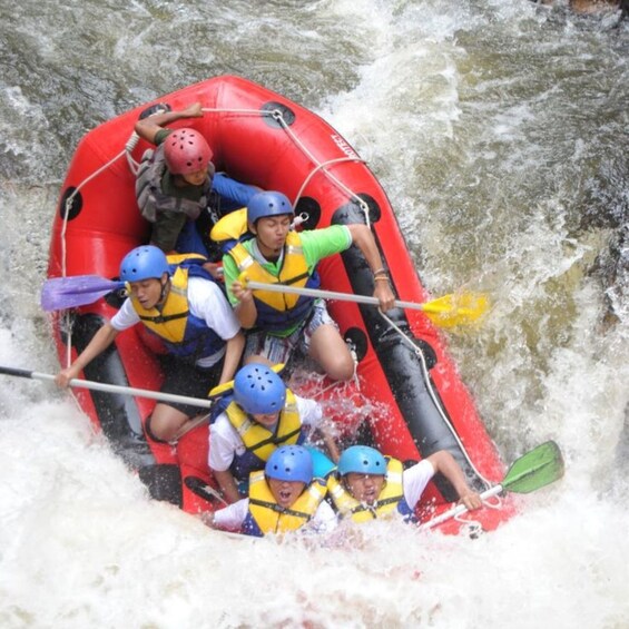 A group of people in a red inflatable raft navigating through a river with rapids. 5