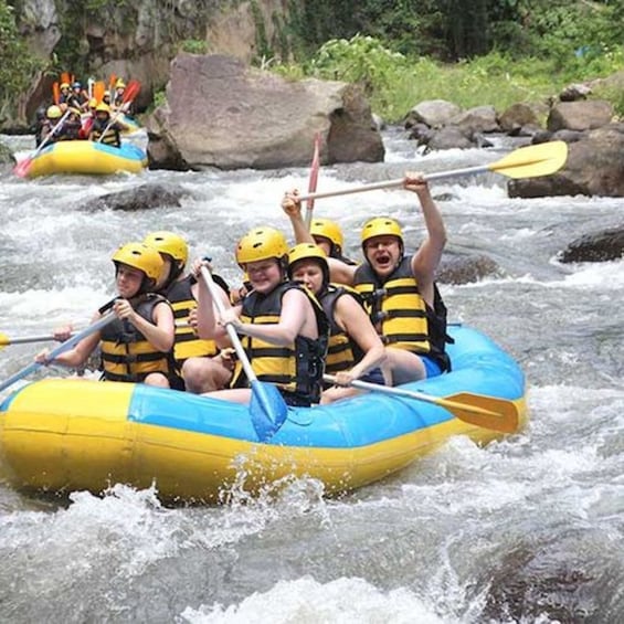 A group of people in a yellow and blue raft navigating a river with rapids. 4
