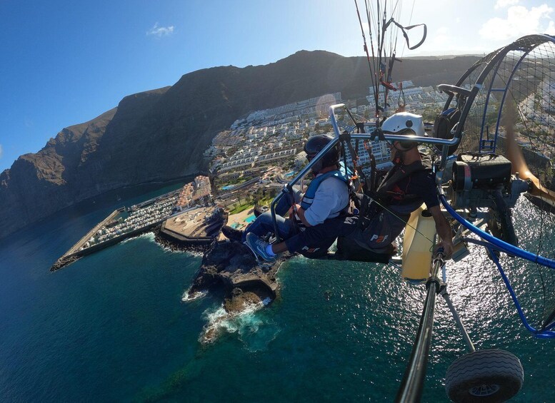 A person bungee jumping from a bridge over a coastal town with mountains in the background. 2