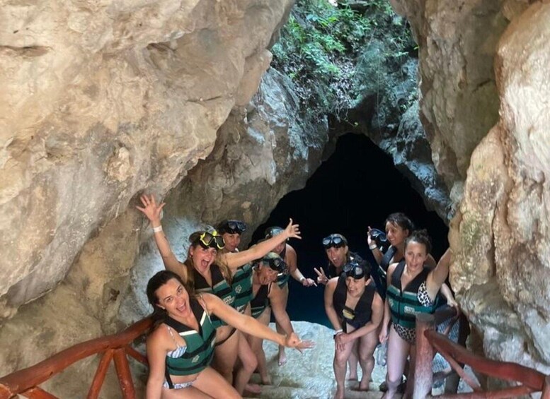 A group of people in a cave with rocky walls and a dark opening. 2