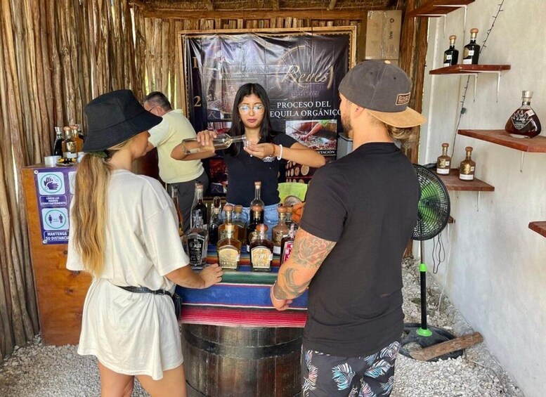 A rustic bar setting with a wooden backdrop, a banner, and various bottles on shelves. 5