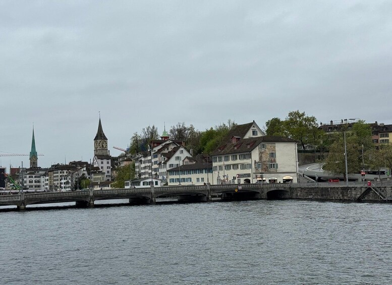 A riverside town with historic buildings, a clock tower, and a bridge. 5