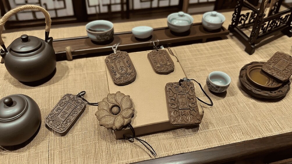 A traditional tea set with a teapot, cups, and decorative items on a woven mat. 2
