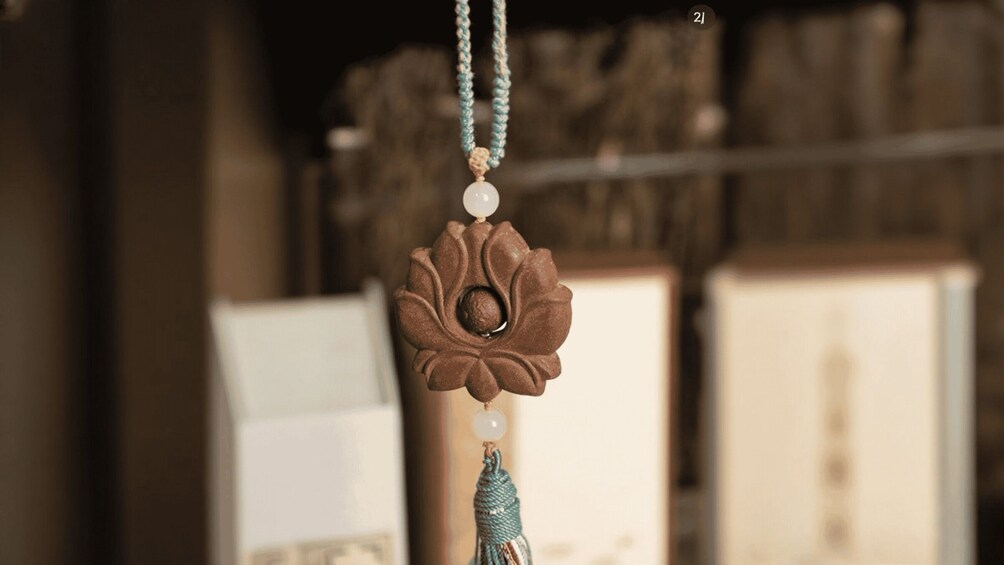 A hanging ornament with a floral design and a bead. 3